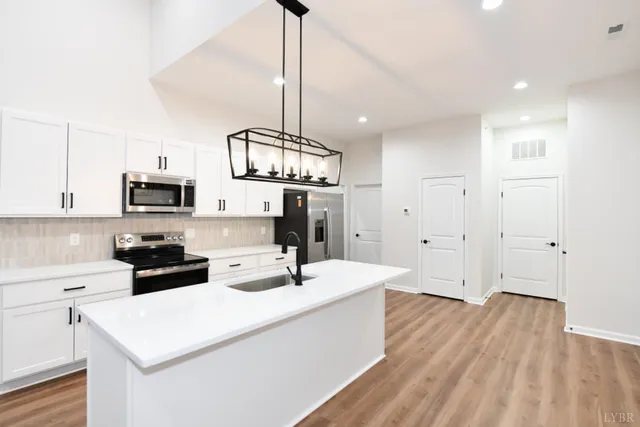 a view of a kitchen with kitchen island a sink wooden floor and a large window