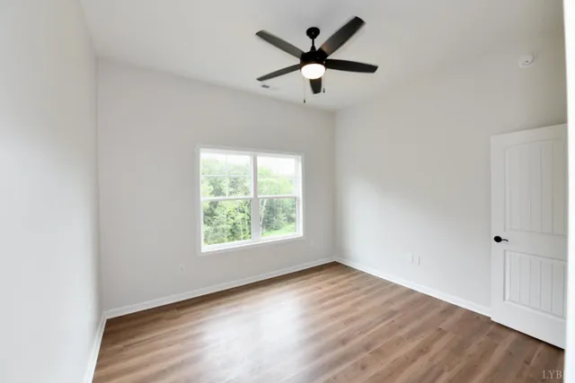 an empty room with a window and a fan