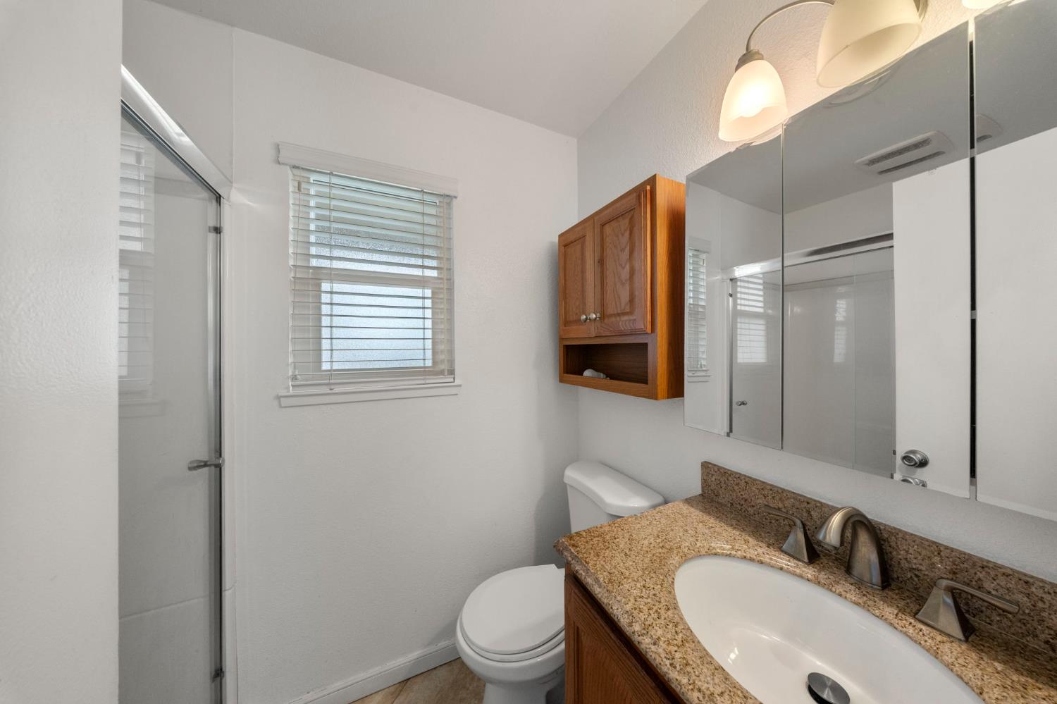 1120 Shasta Avenue Modesto, CA 95358 - Photo 19 of 35 a bathroom with a granite countertop toilet sink and mirror