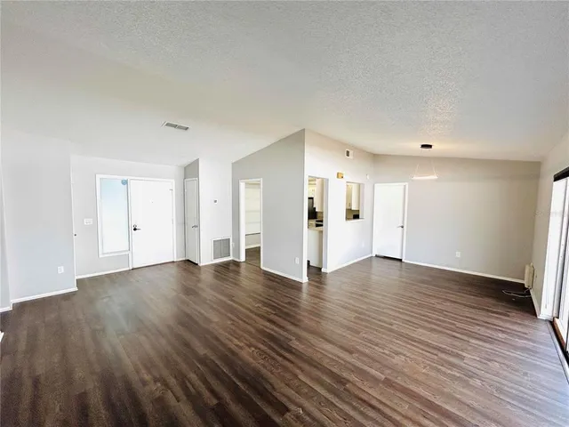 a view of an empty room with wooden floor and closet