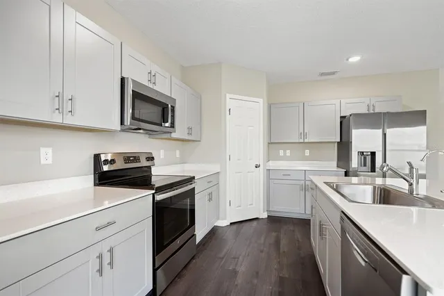 a kitchen with granite countertop white cabinets sink and stainless steel appliances