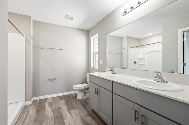 a bathroom with a sink a toilet a shower and a mirror