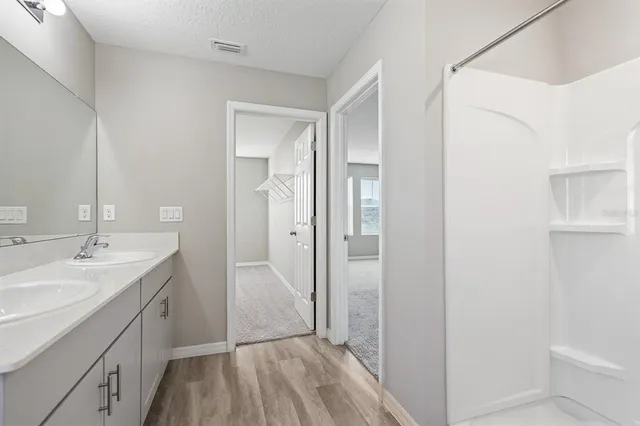 a spacious bathroom with a double vanity sink a mirror and a shower