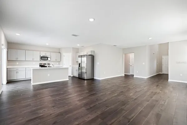 a kitchen with stainless steel appliances granite countertop a refrigerator a sink dishwasher a stove top oven a refrigerator and white cabinets with wooden floor