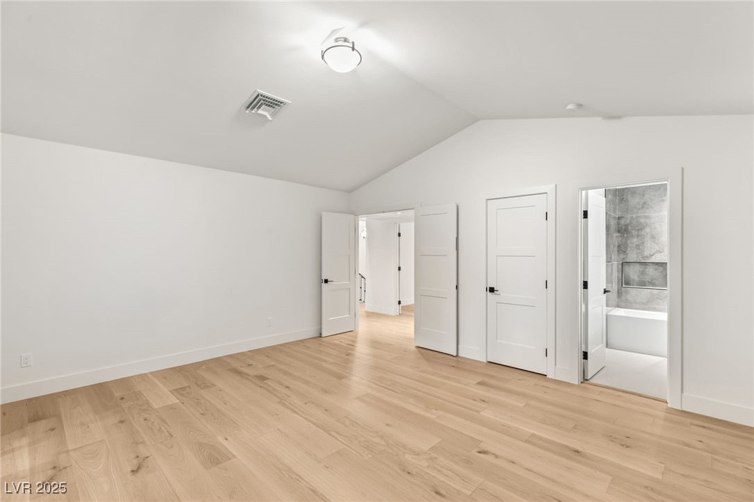 2316 Prometheus Court Henderson, NV 89074 - Photo 49 of 92 Unfurnished bedroom featuring light wood-style floors, visible vents, connected bathroom, and lofted ceiling