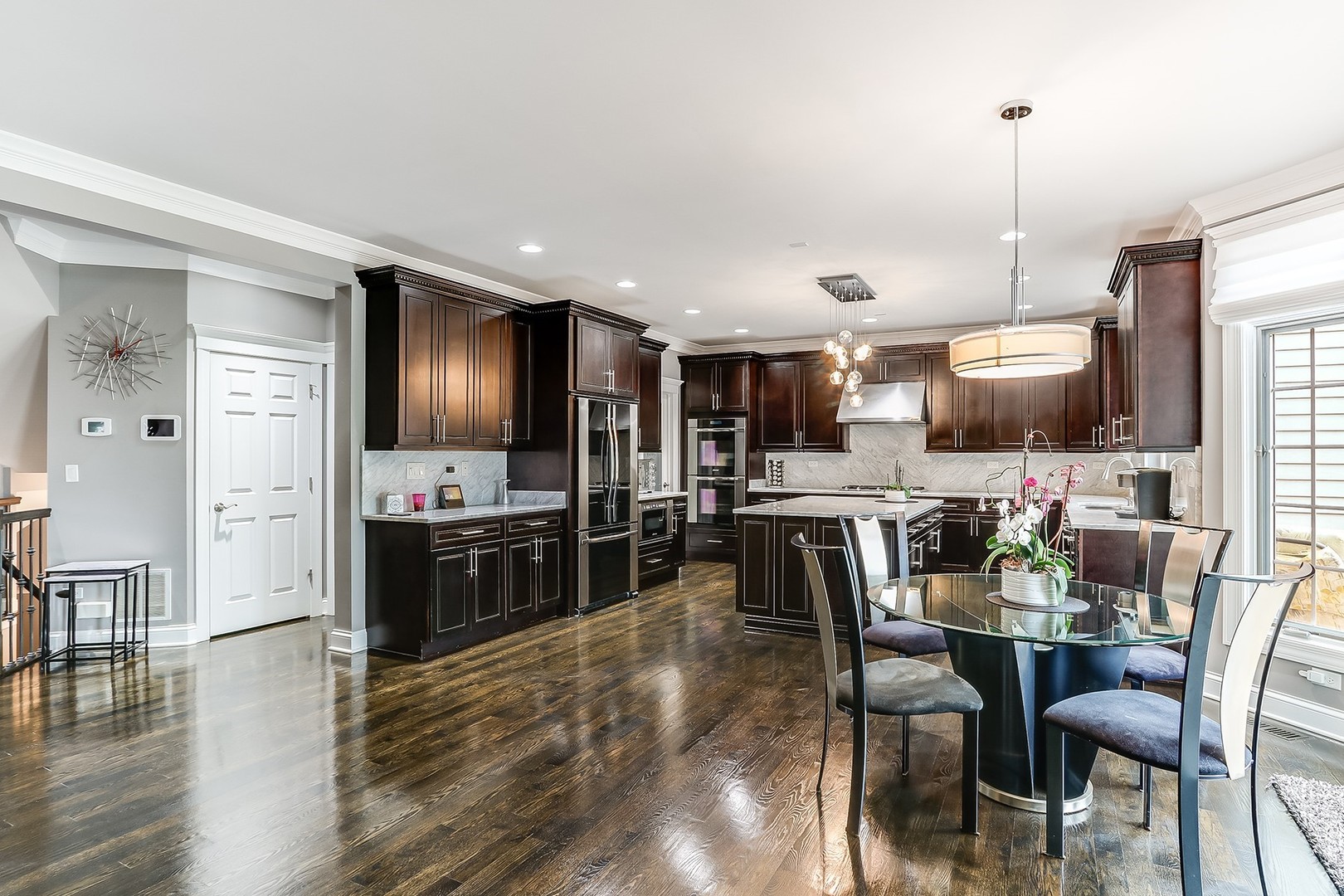 1839 Rizzi Lane Bartlett, IL 60103 - Photo 18 of 50 a kitchen with stainless steel appliances kitchen island granite countertop a refrigerator a stove a dining table and chairs with wooden floor