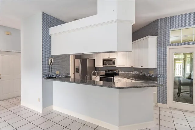 a kitchen with stainless steel appliances granite countertop a sink a stove and white cabinets