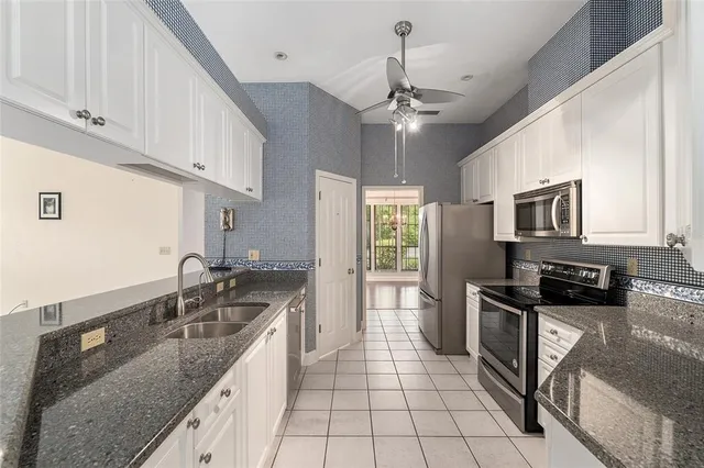 a kitchen with granite countertop white cabinets stainless steel appliances and a counter space