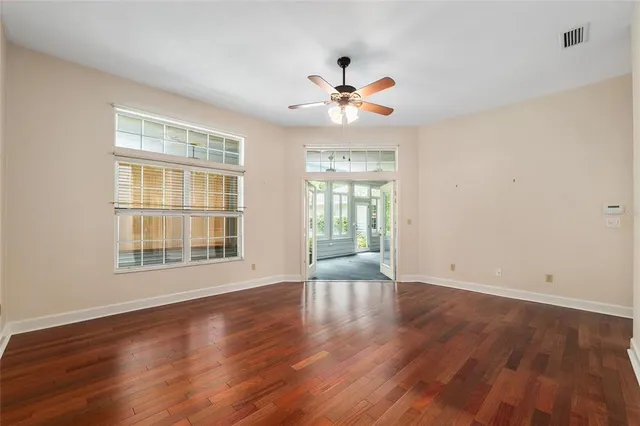a view of an empty room with a window and wooden floor