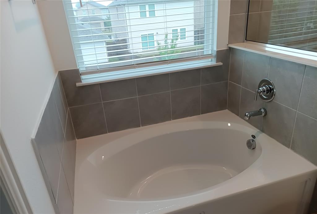 505 Virginia Way Princeton, TX 75407 - Photo 6 of 22 a white bath tub sitting in a bathroom next to a window