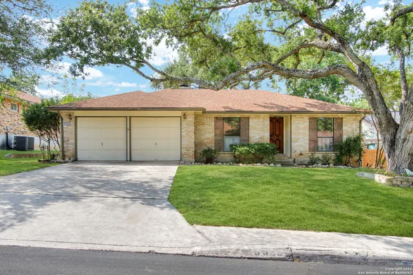 a front view of a house with a garden and trees