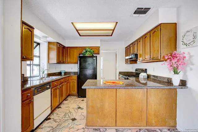 a kitchen with stainless steel appliances granite countertop a sink refrigerator and cabinets