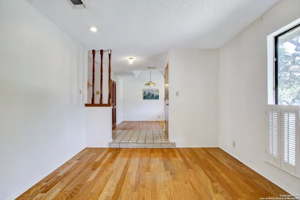 a view of empty room with wooden floor and fan