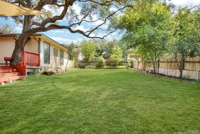 a view of a house with a big yard and large trees