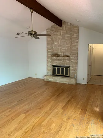 a view of empty room with a fireplace and a ceiling fan