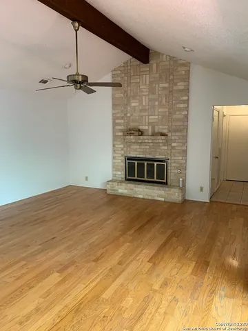a view of empty room with a fireplace and a ceiling fan