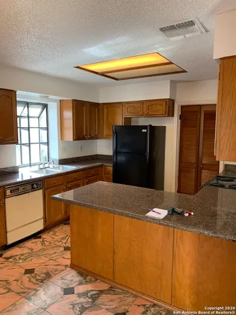 a kitchen with stainless steel appliances granite countertop a sink and a refrigerator