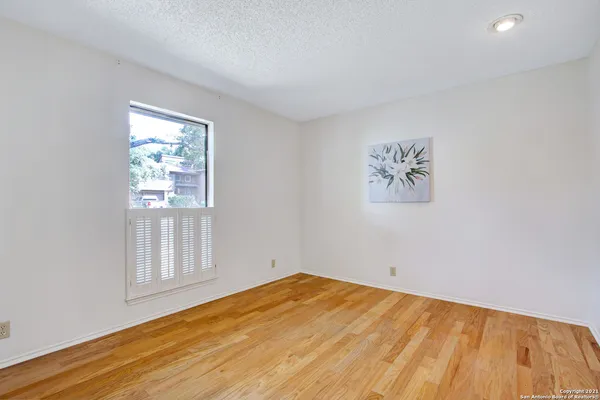 a view of empty room with wooden floor and fan