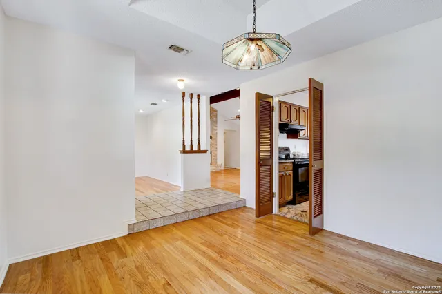 a view of an empty room with wooden floor and a kitchen