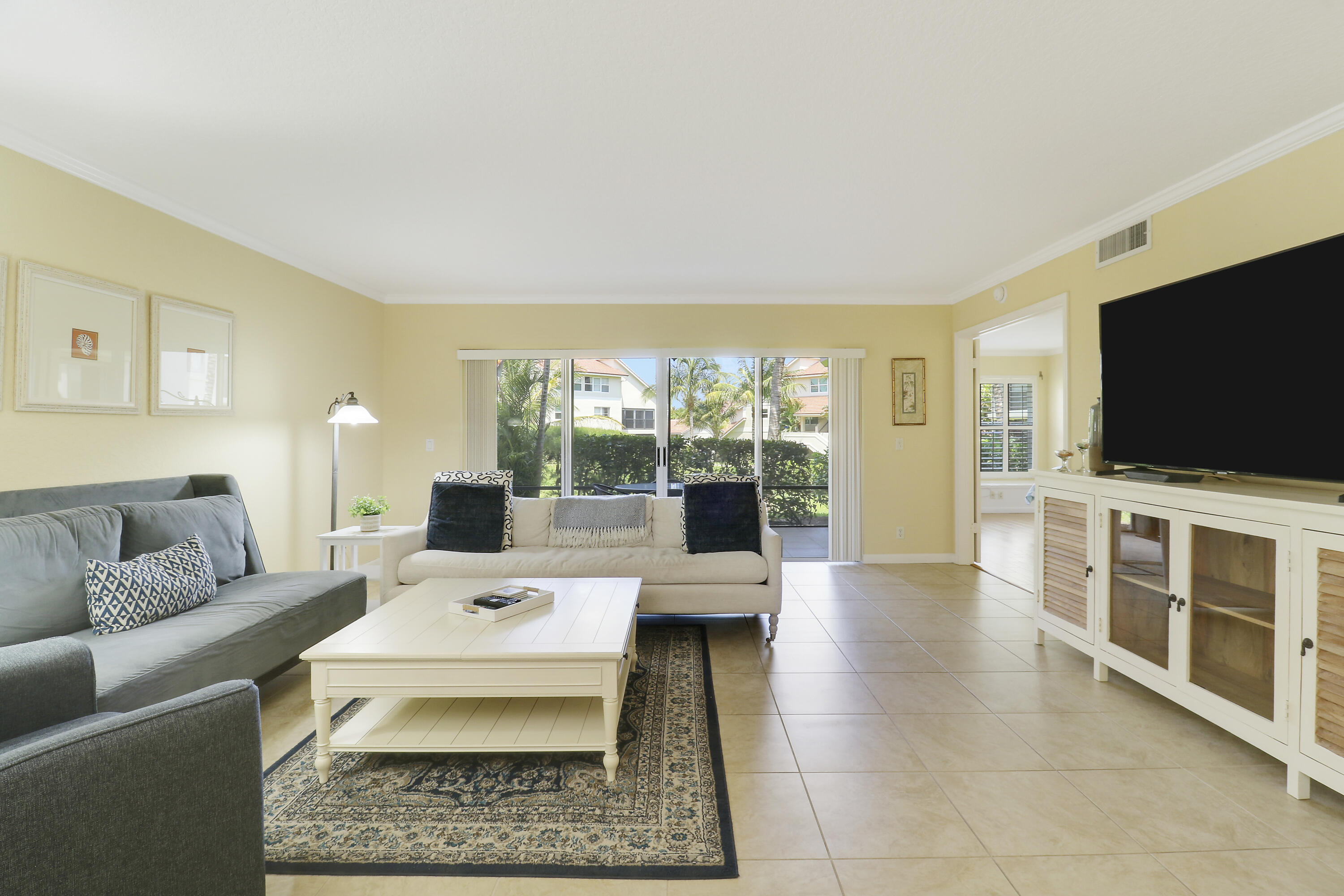 4161 U.S. Highway 1, Unit C2 Jupiter, FL 33477 - Photo 8 of 57 a living room with furniture a flat screen tv and a floor to ceiling window