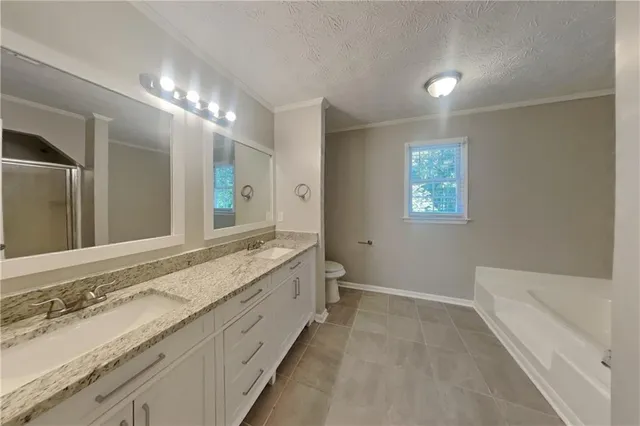 a spacious bathroom with a granite countertop double vanity sink a mirror and a bathtub