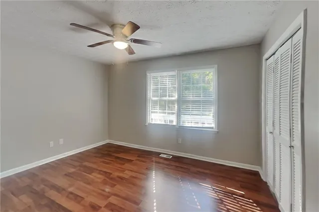 a view of an empty room with wooden floor and a window