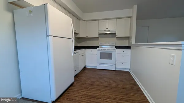 a kitchen with stainless steel appliances a refrigerator and white cabinets