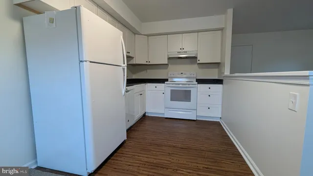a kitchen with stainless steel appliances a refrigerator and white cabinets