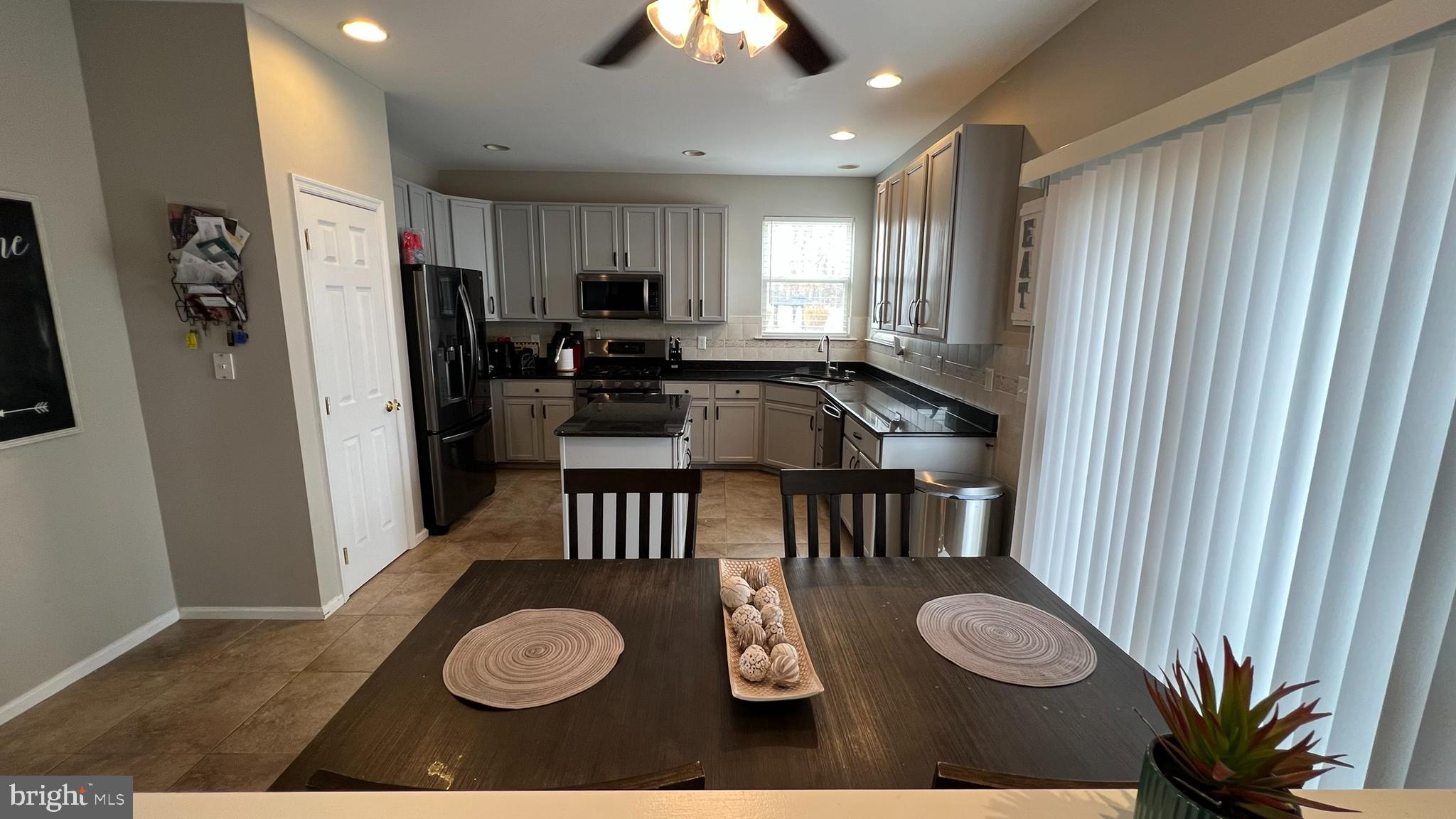 415 Stockton Loop Williamstown, NJ 08094 - Photo 13 of 41 a kitchen with stainless steel appliances a dining table chairs and a refrigerator