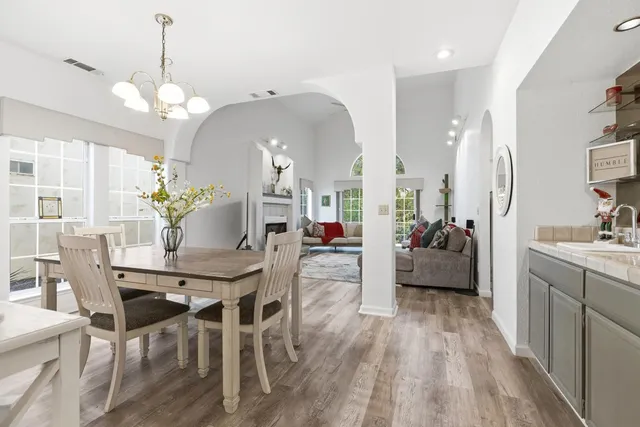 a view of a dining room and livingroom with furniture wooden floor a chandelier