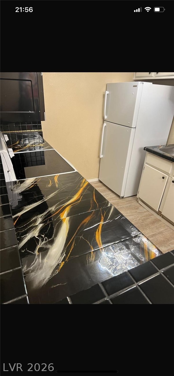 5131 South Lindell Road, Unit 205 Las Vegas, NV 89118 - Photo 9 of 22 Kitchen with dark countertops, freestanding refrigerator, and white cabinets