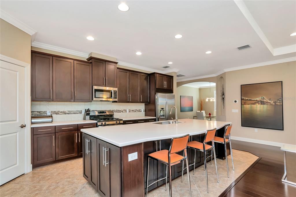 12848 Del Corso Loop Lakewood Ranch, FL 34211 - Photo 15 of 70 a kitchen with a sink a stove a refrigerator and chairs