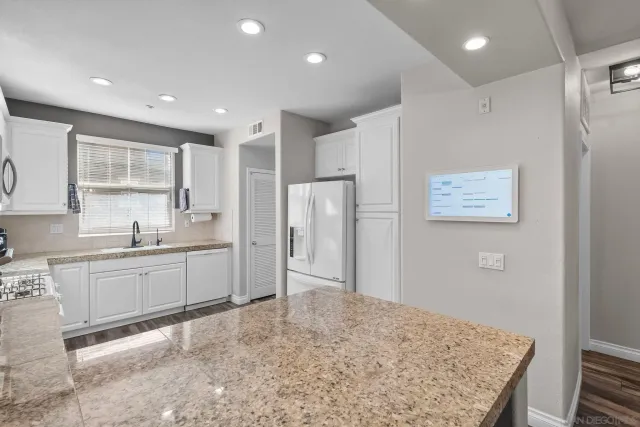 a kitchen with stainless steel appliances granite countertop a sink stove and white cabinets with wooden floor
