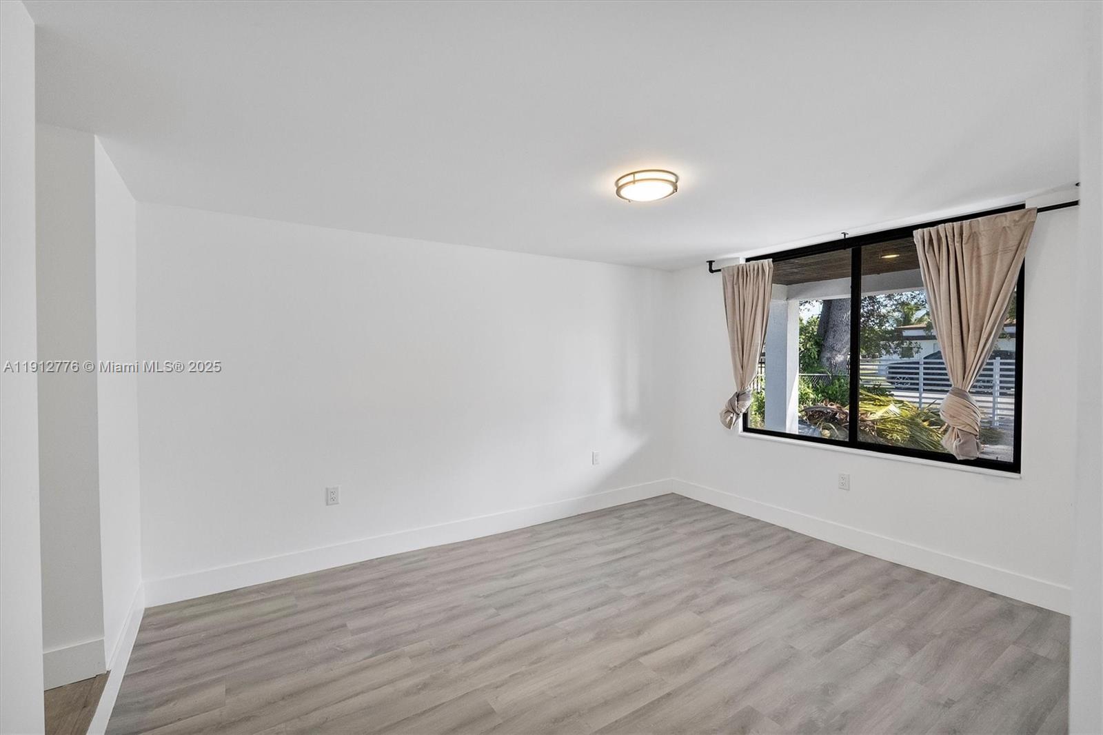 11730 Northwest 3rd Avenue Miami, FL 33168 - Photo 6 of 22 an empty room with wooden floor and windows