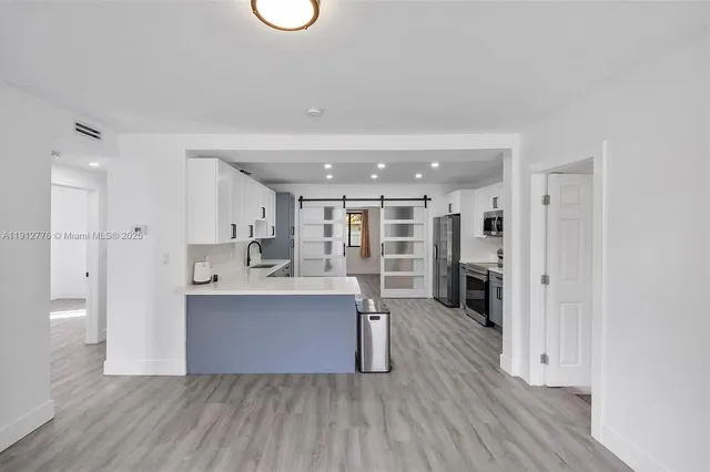a large white kitchen with wooden floor and a sink