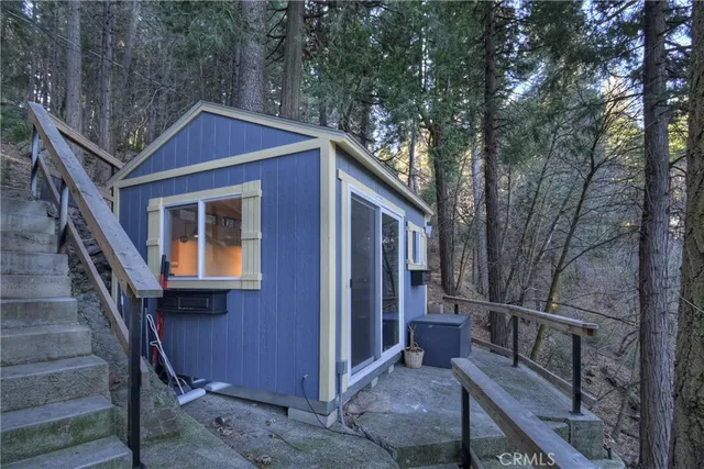a view of wooden house with a large tree and wooden fence
