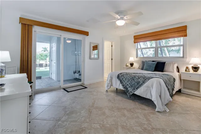 a bedroom with a large bed a chandelier and windows