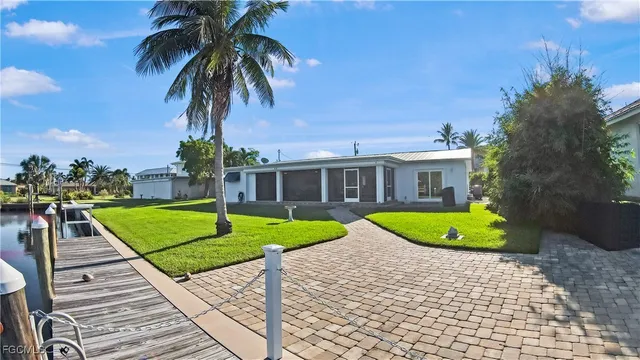a view of a house with a yard and palm trees