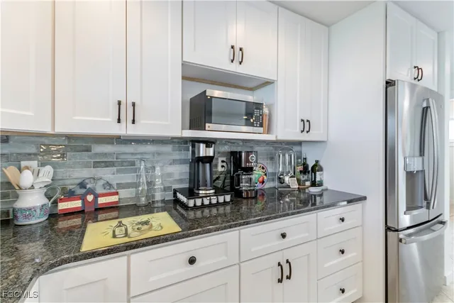 a kitchen with stainless steel appliances granite countertop a refrigerator and white cabinets