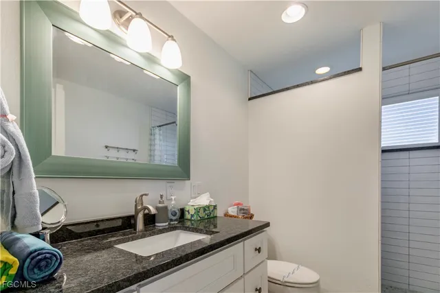 a bathroom with a granite countertop sink mirror and toilet