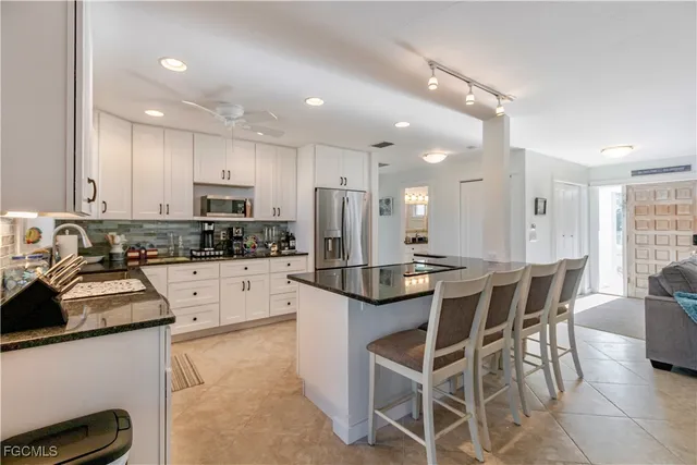 a kitchen with stainless steel appliances kitchen island granite countertop a refrigerator a stove a sink a dining table and chairs