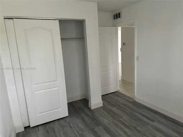 an empty room with wooden floor and entrance