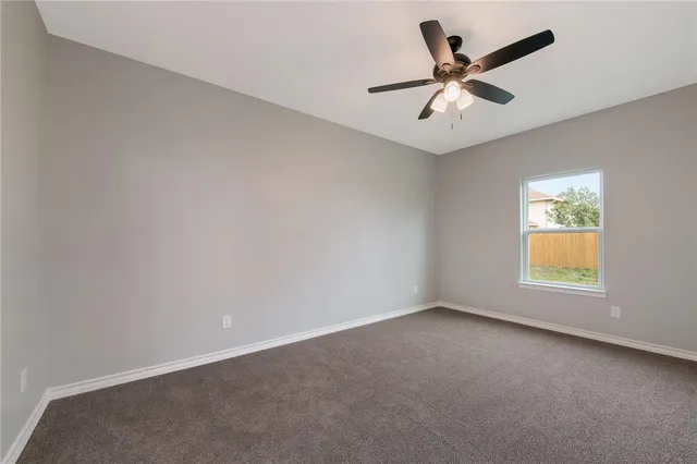 an empty room with a window and a ceiling fan