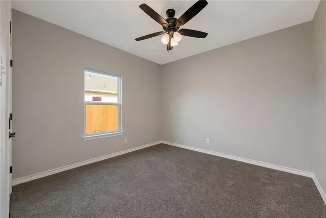 an empty room with a window and a ceiling fan
