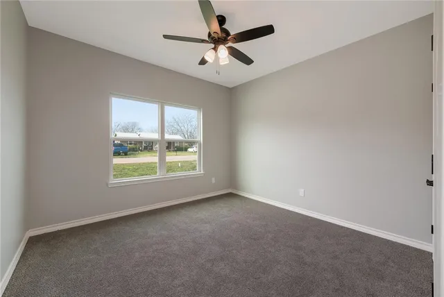an empty room with a window and a fan