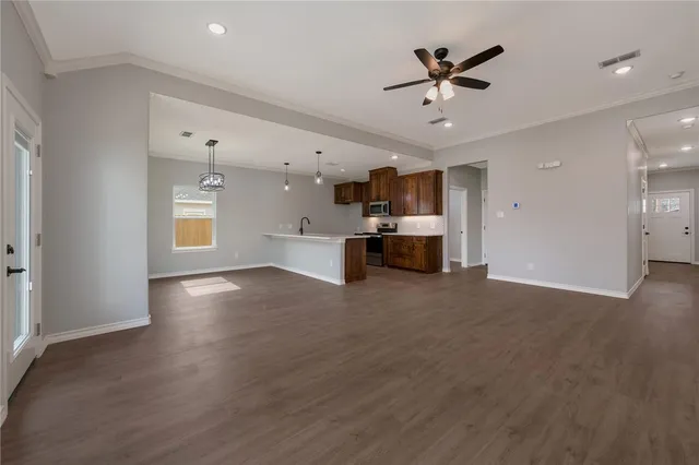 wooden floor in kitchen and an empty room with a ceiling fan