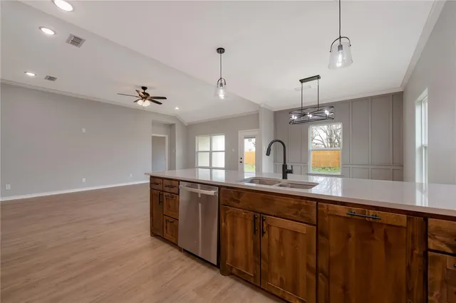 a large kitchen with stainless steel appliances a sink and wooden floor