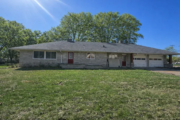 a view of a house with a yard and a large tree