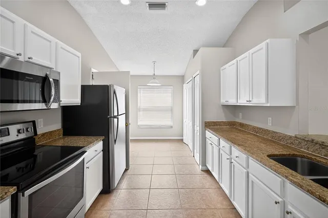 a kitchen with granite countertop a refrigerator and a stove top oven