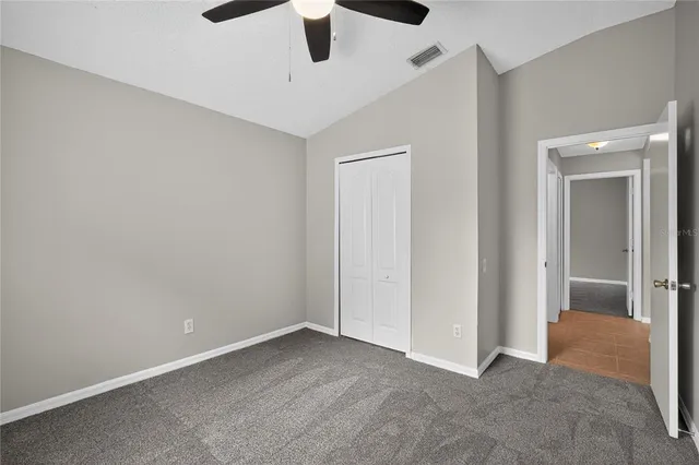 an empty room with ceiling fan and window